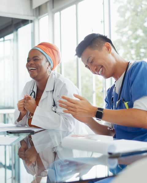 Two coworkers smiling while in a medial office setting.