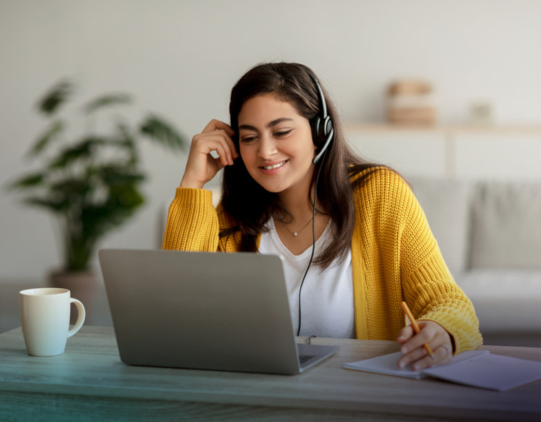 Woman wearing a headset while sitting in front of a laptop.