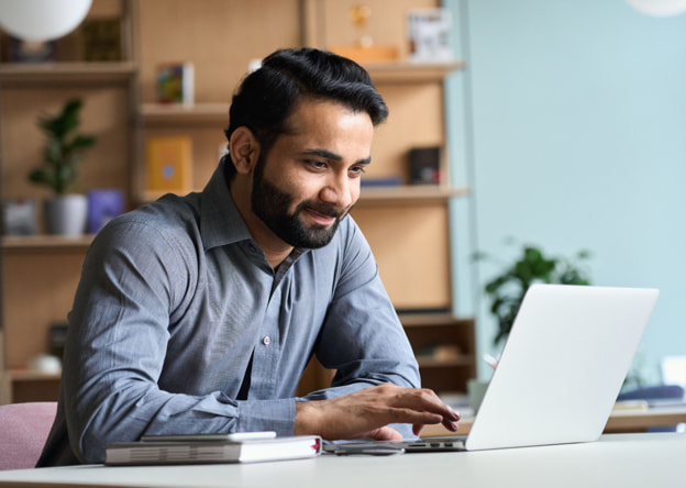 Man working at a laptop in a colorful office setting.