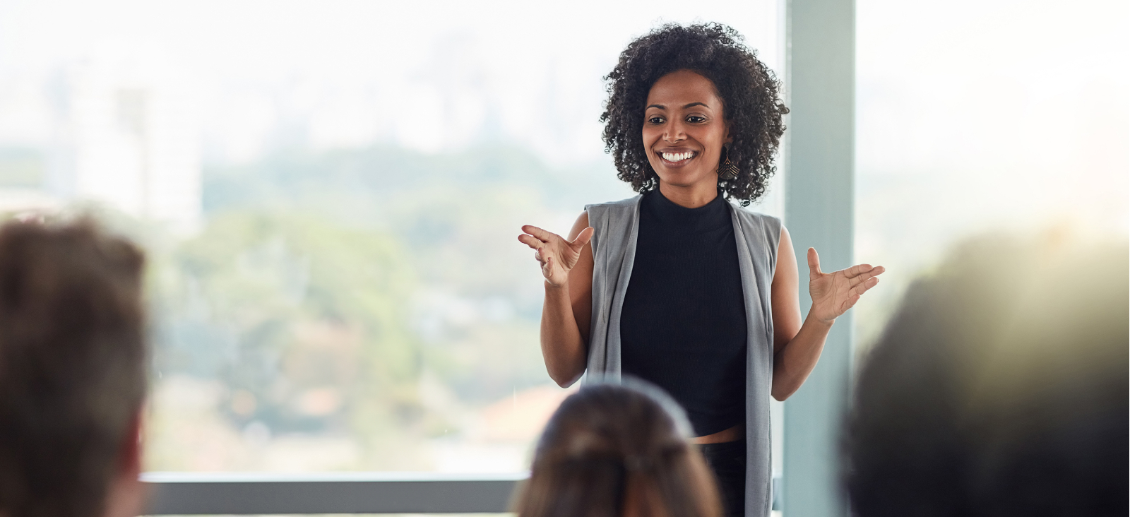Smiling woman presenting to a group, with a 56 out of 60 scale and a blue ‘Inspire a Shared Vision’ leadership behavior banner in the bottom right corner.